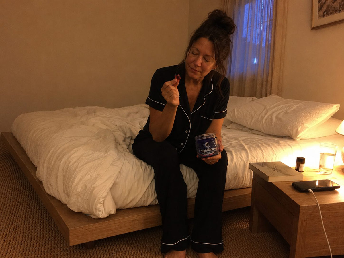 A woman holding the open NightBloom jar and one gummy as part of her bedtime ritual