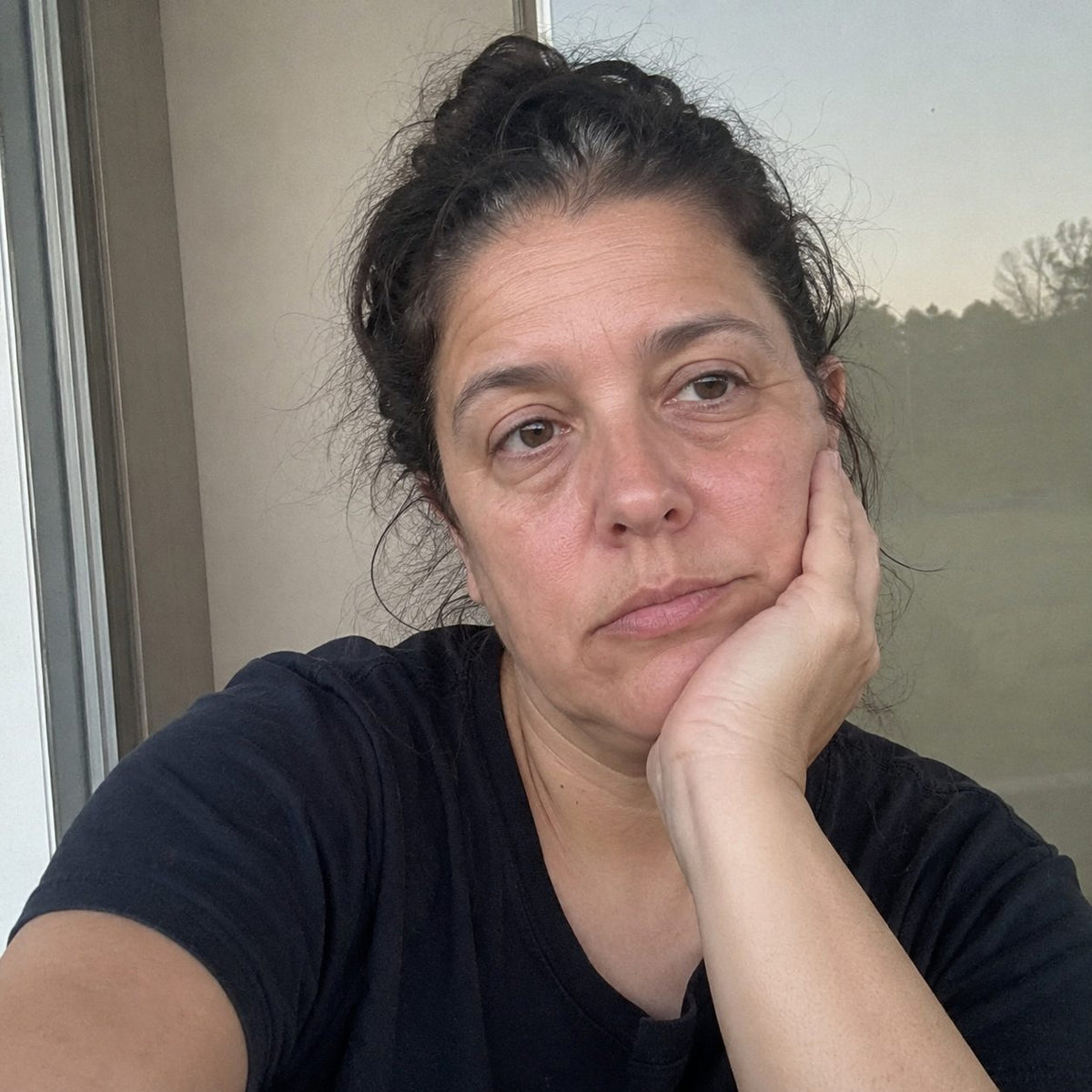 A tired woman looking at her reflection after another broken night of sleep