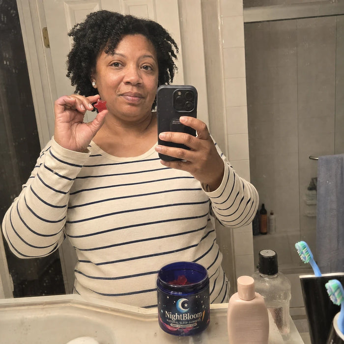 A NightBloom customer holding her gummies in a bathroom mirror photo
