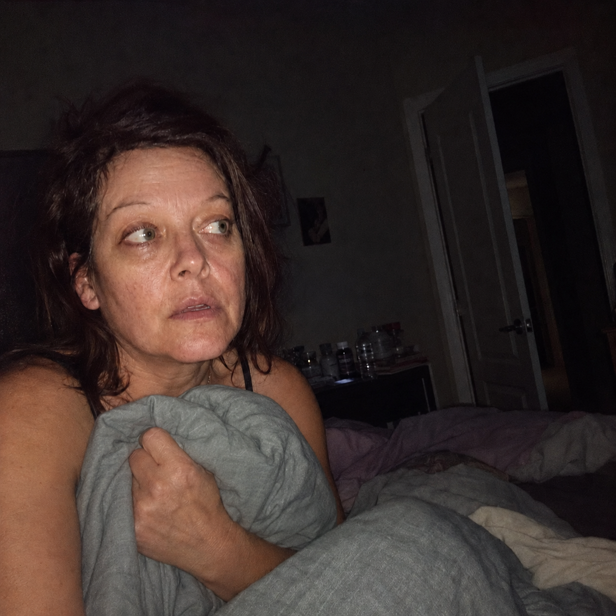 A tired woman awake in bed after a vivid nightmare